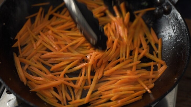 Shredded carrots are cooked soft in a skillet