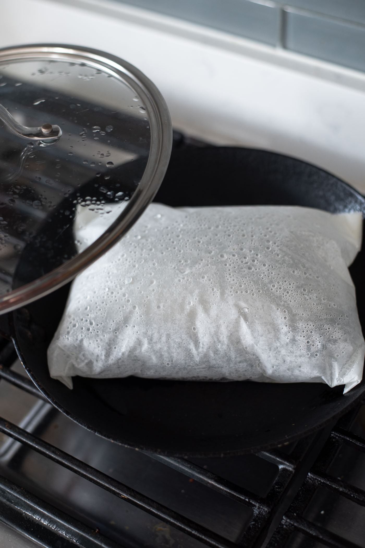 Mackerel in a parchment pouch puffing up in a skillet.