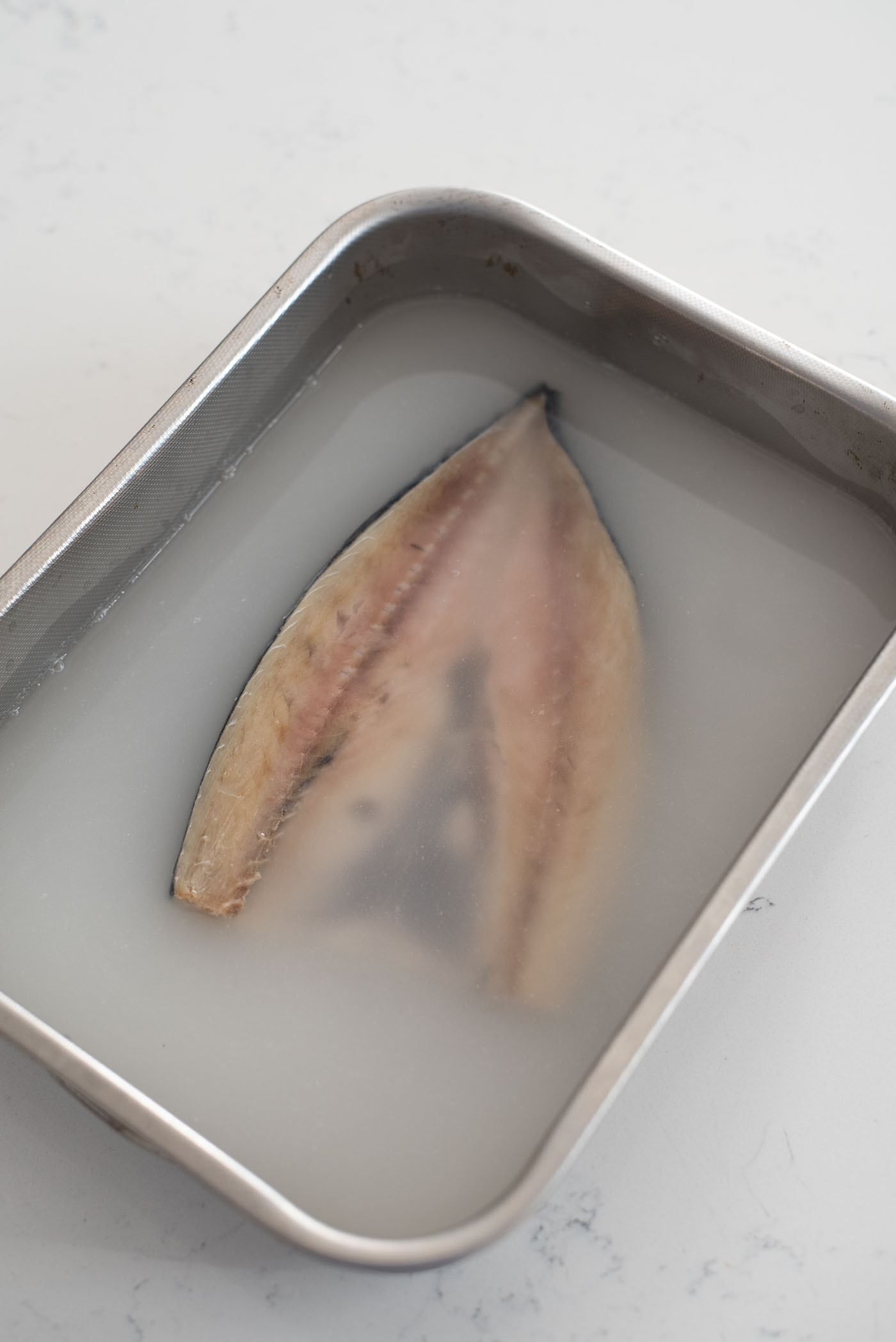 Salted mackerel fish soaking in a rice water.