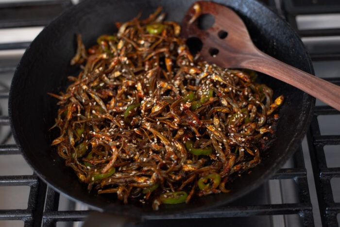 Dried anchovies are tossed with gochujang sauce in a skillet