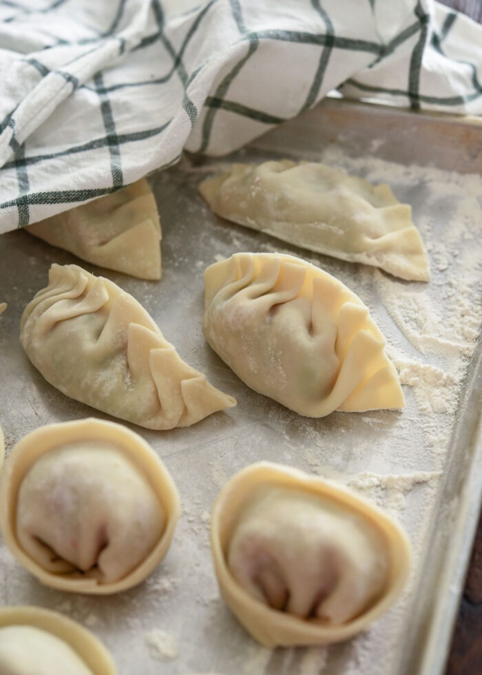 Pleated homemade Korean dumplings are laid on a sheet covered with a towel