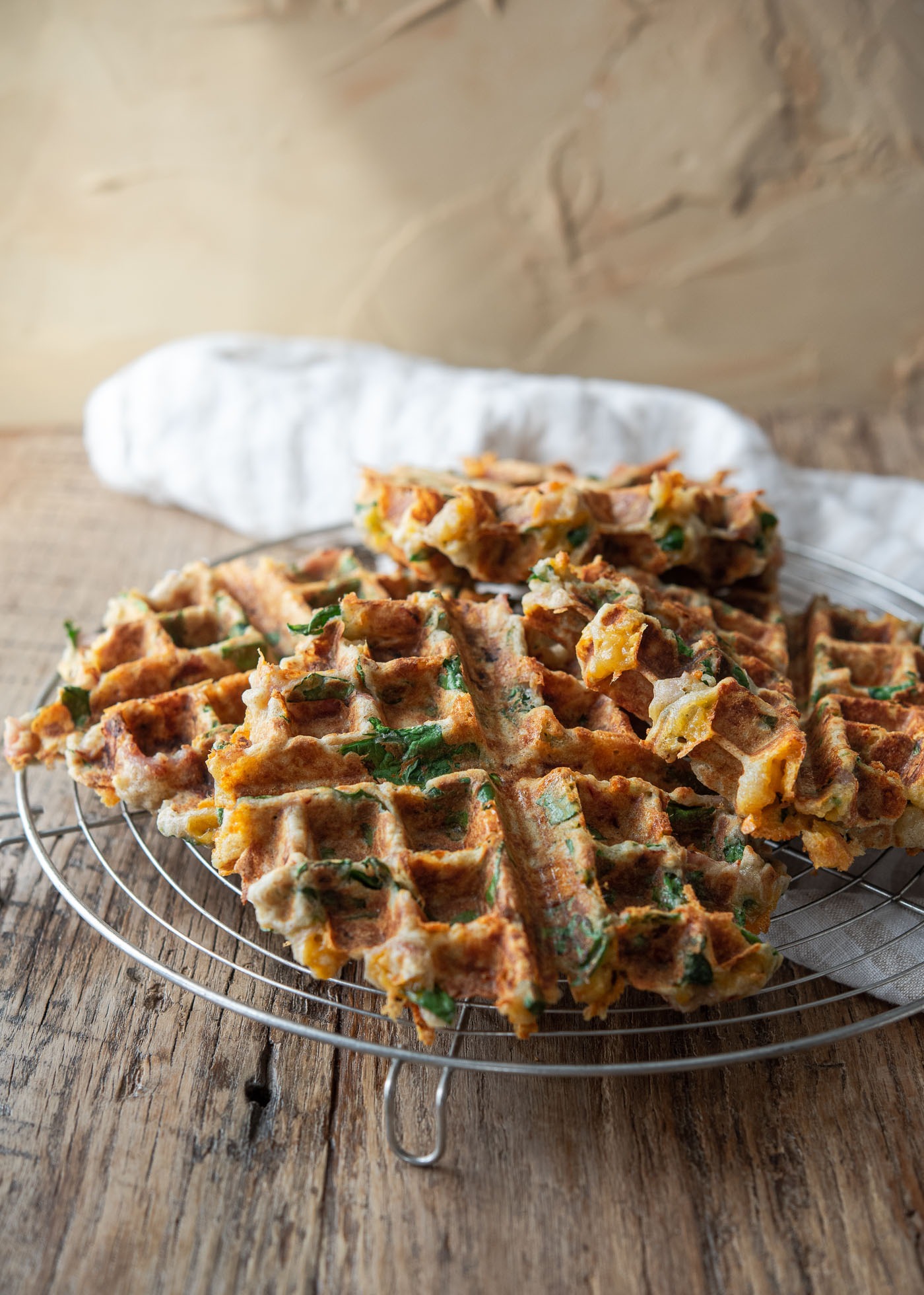 Freshly cooked savory waffles cooling on a wire rack to stay crisp.