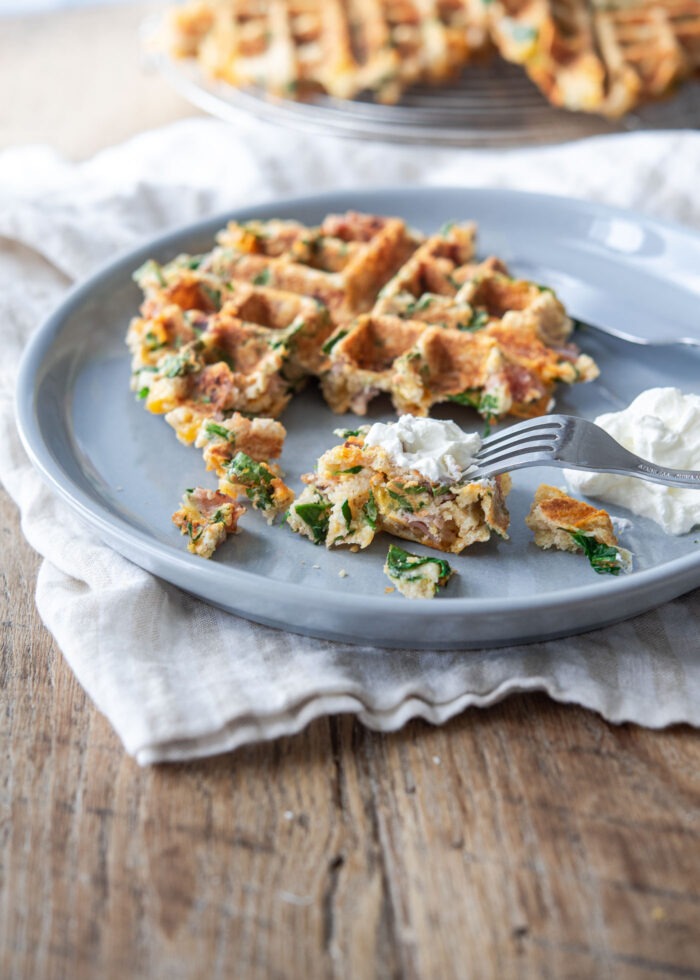 Savory waffles are served with sour cream on a blue plate.