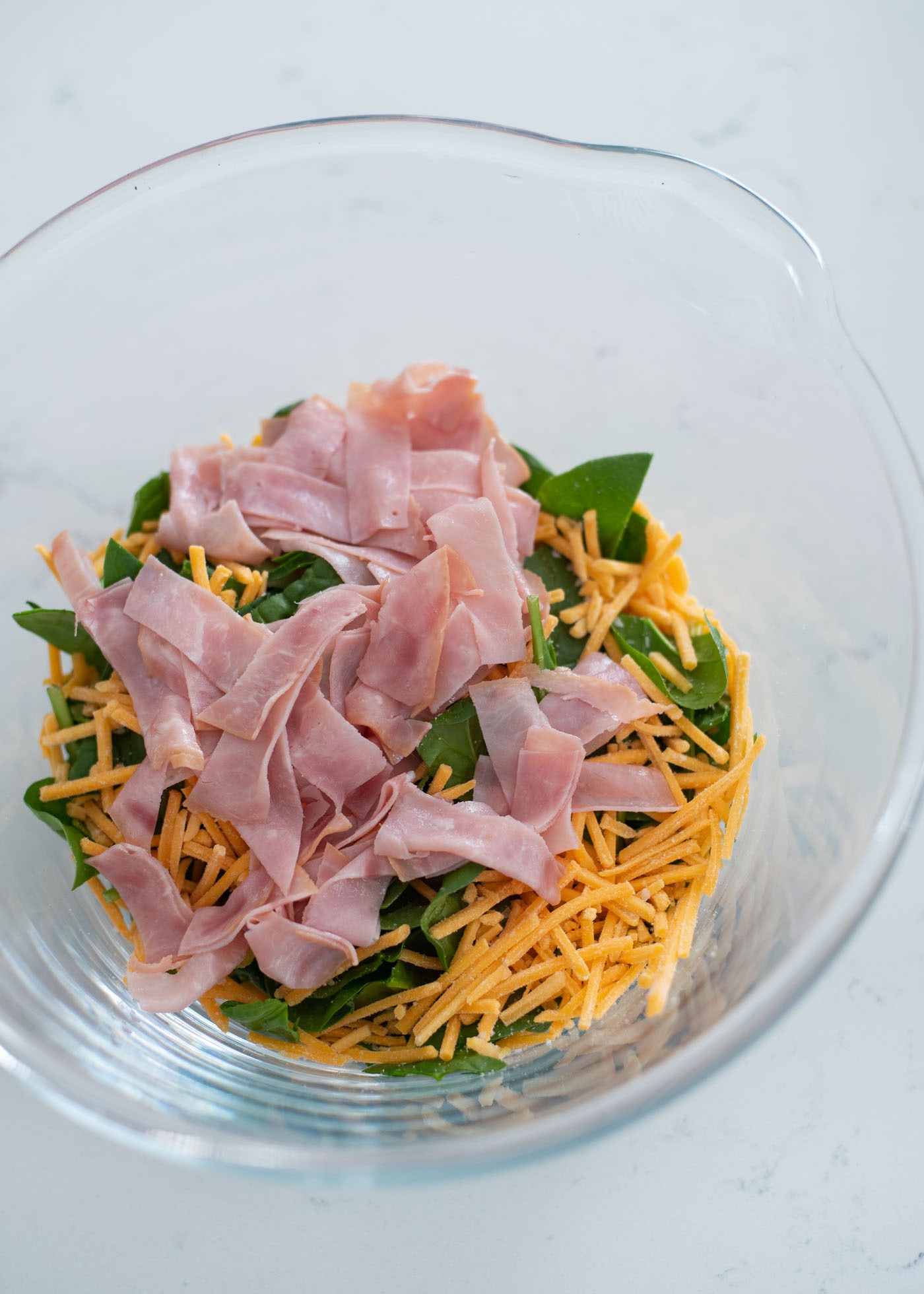 Spinach, sliced ham, grated cheese are combined in a mixing bowl