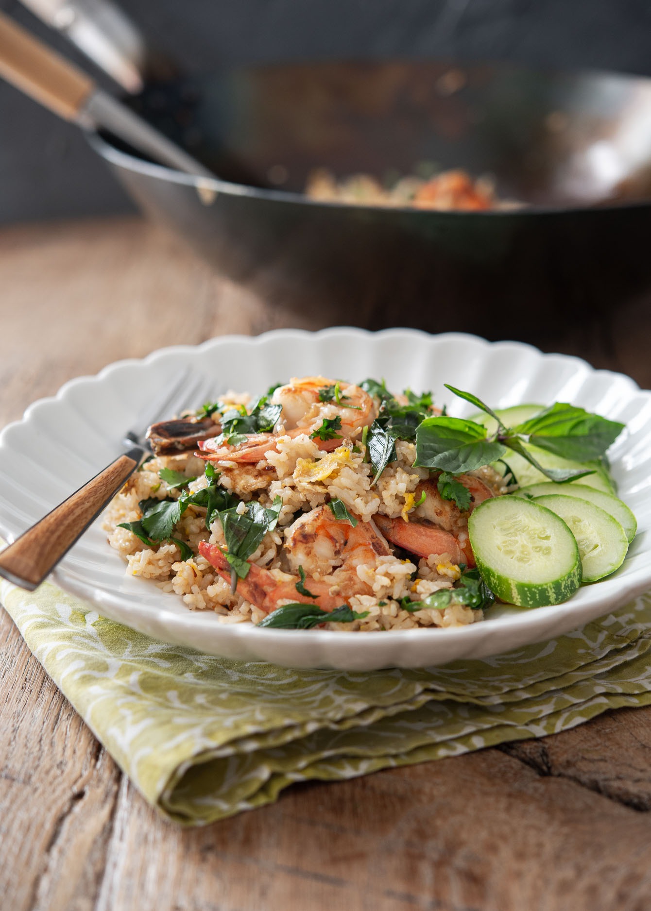 Thai basil fried rice with shrimp is served on a white plate with cucumber slices