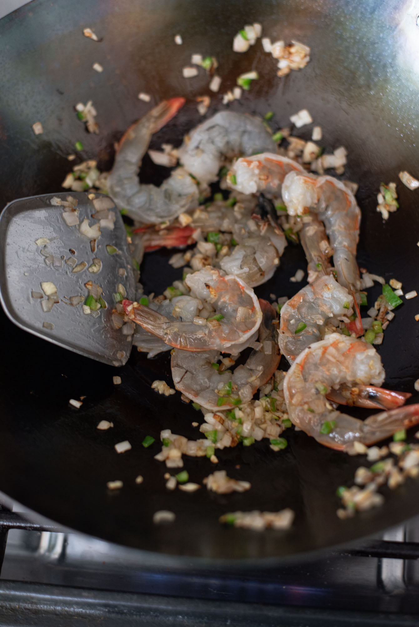 Shrimp is added to a wok to stir fry with shallot and chili mix