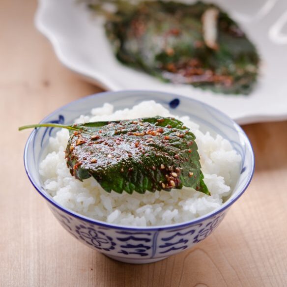 A seasoned and steamed perilla leaf is on a bowl of rice