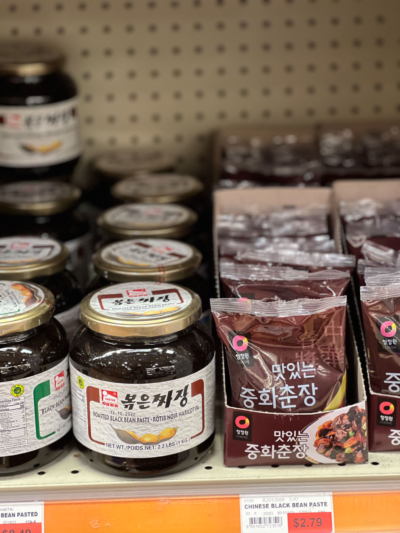 Korean black bean pastes in jars and plastic bags are on the shelf.
