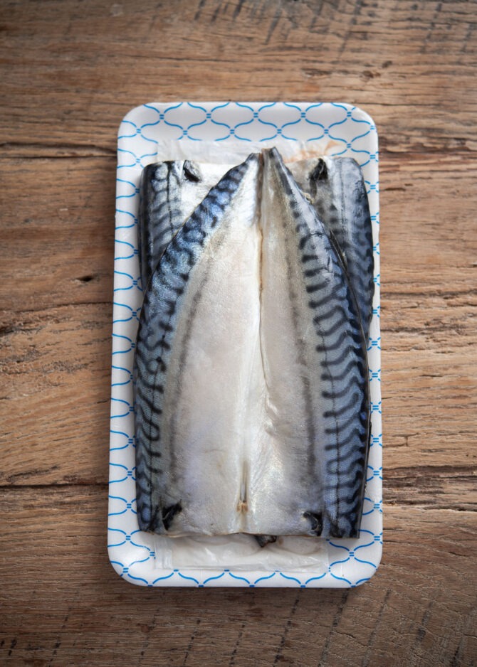 Salted mackerel fillets are stacked together on a plate