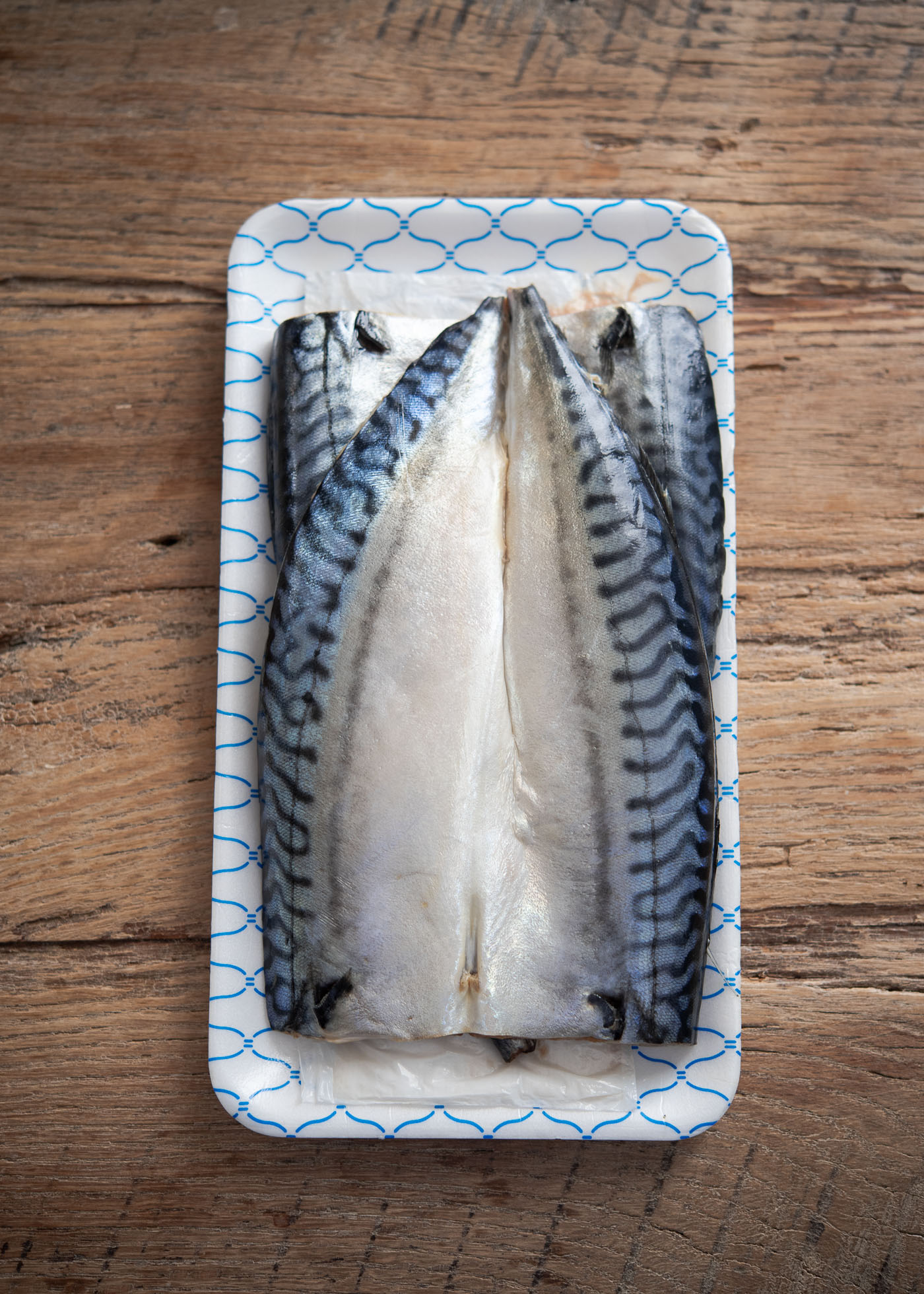 Salted mackerel fish fillets are stacked together on a plate
