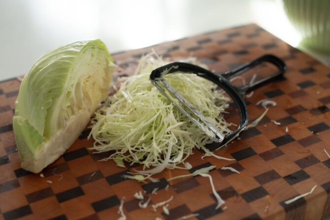 Green cabbage is finely shredded with a vegetable peeler