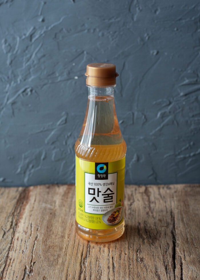 A bottle of Korean sweet rice wine shows its golden color.