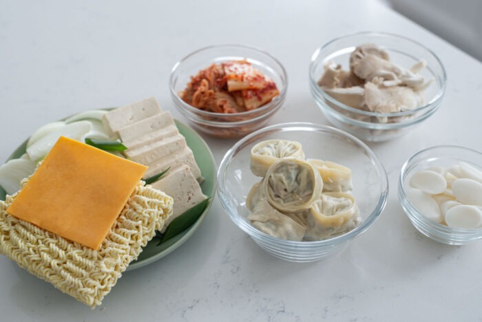 More Korean army stew ingredients are laid on a counter to display.