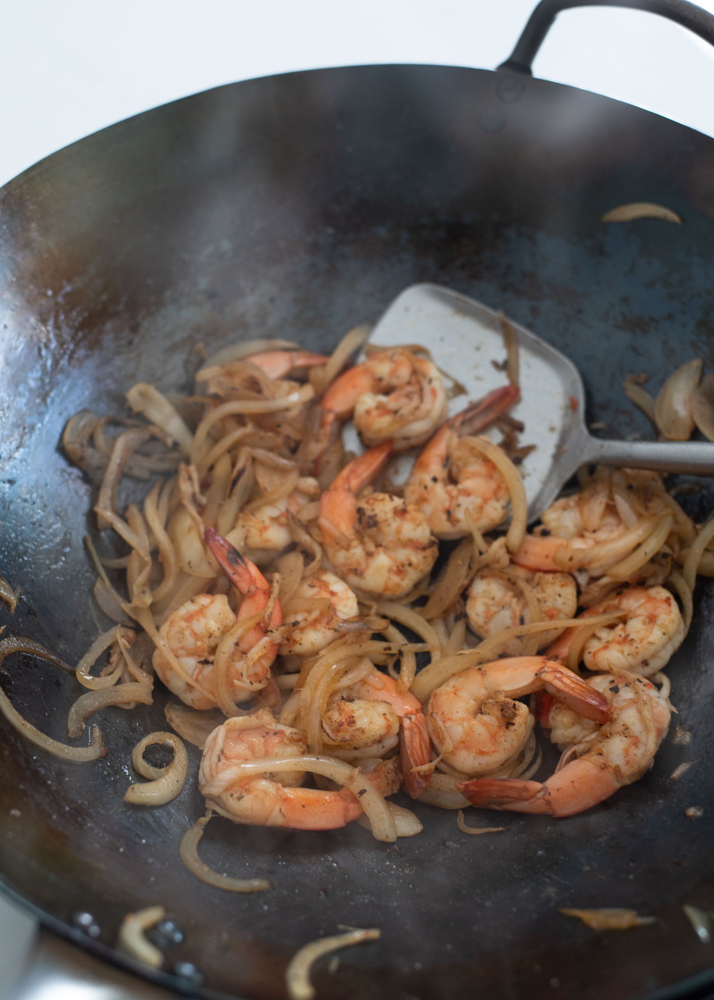 Onion and shrimp are cooked in a wok.