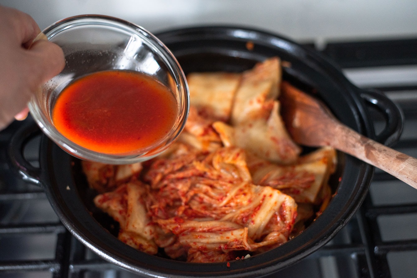 kimchi juice added into a pot of kimchi and pork belly stew.