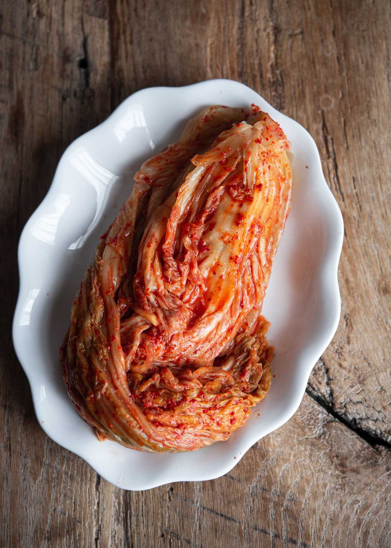 A head of fermented cabbage kimchi on a white plate.