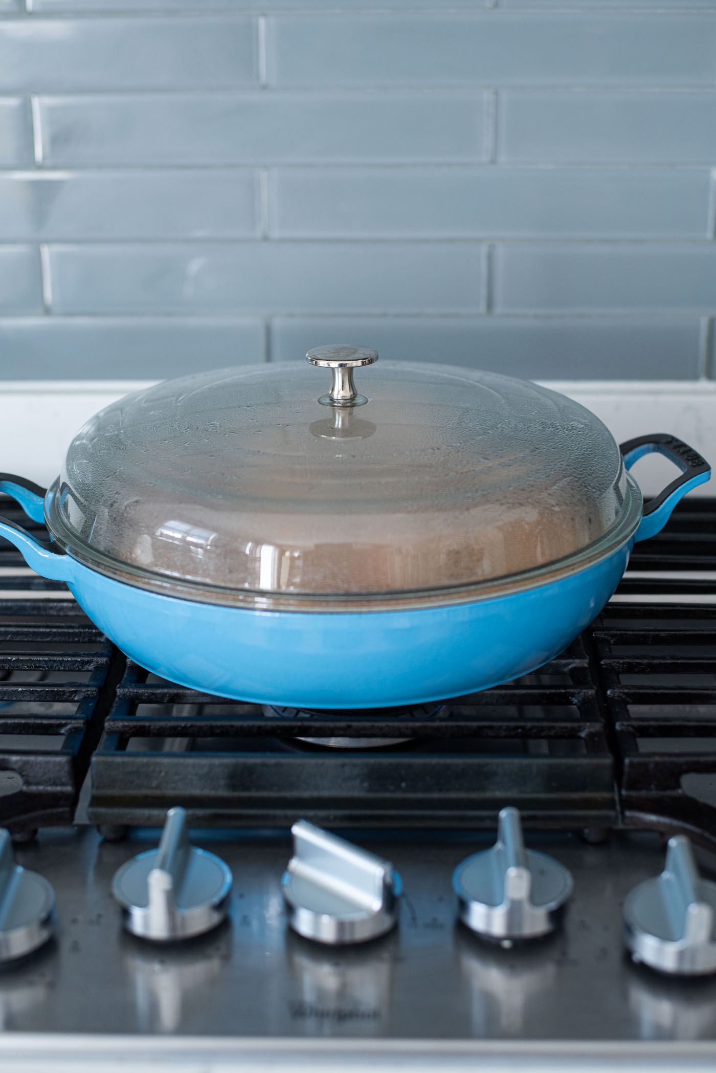 A blue pan is covered with a dome shaped lid and placed on the stove