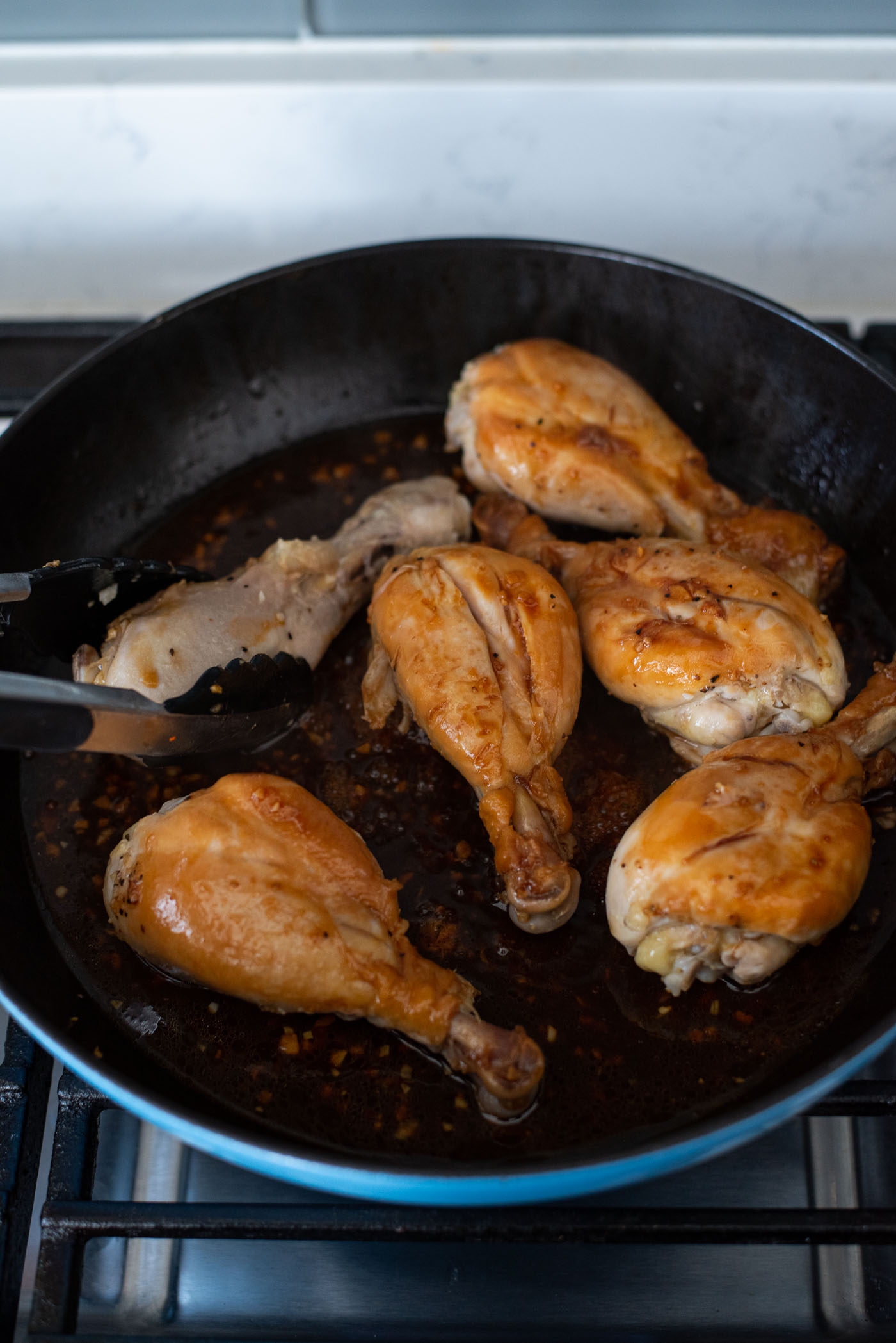 Turn the chicken drumsticks to the other side with kitchen tongs