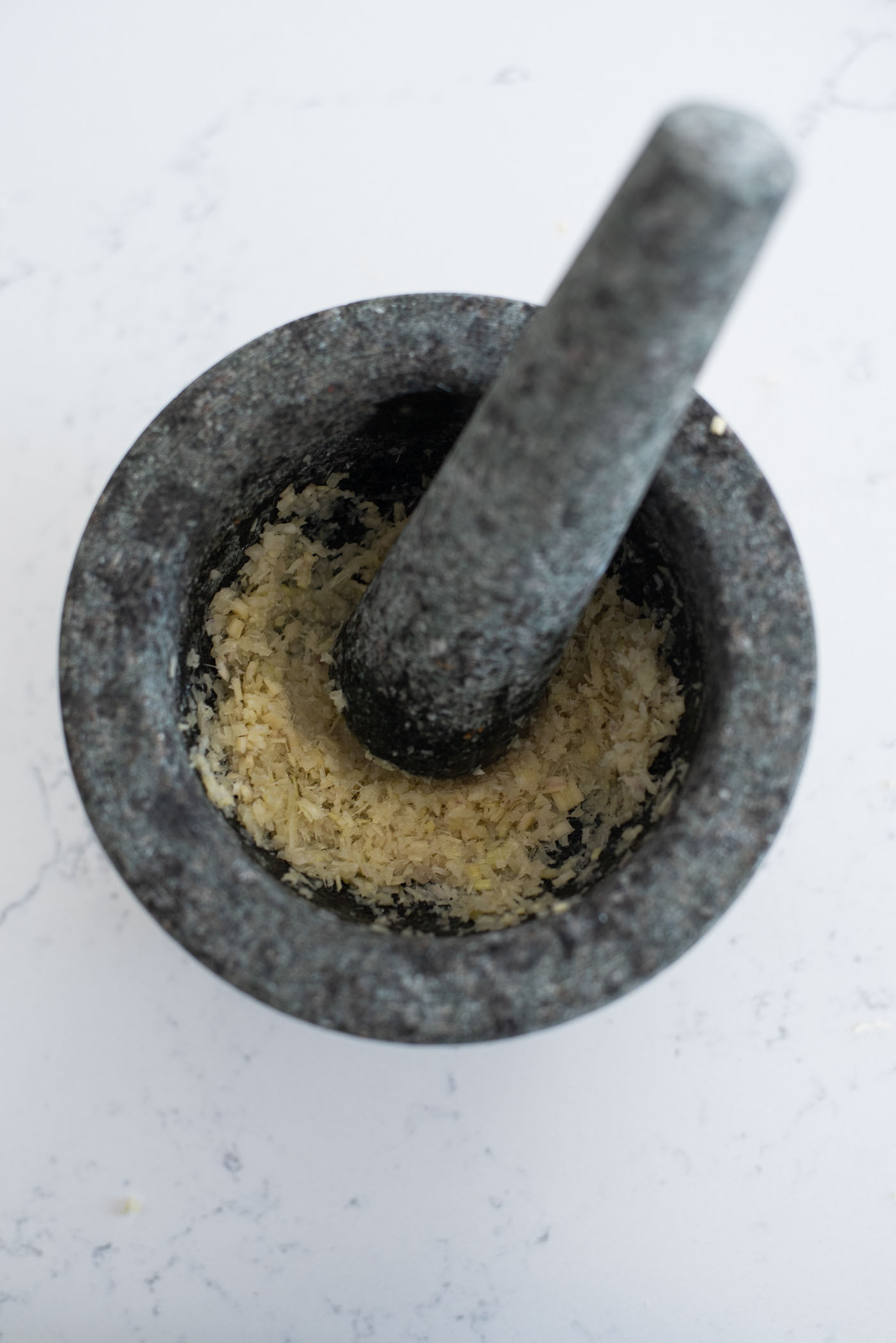 Lemongrass and garlic are pounded in a mortar and pestle
