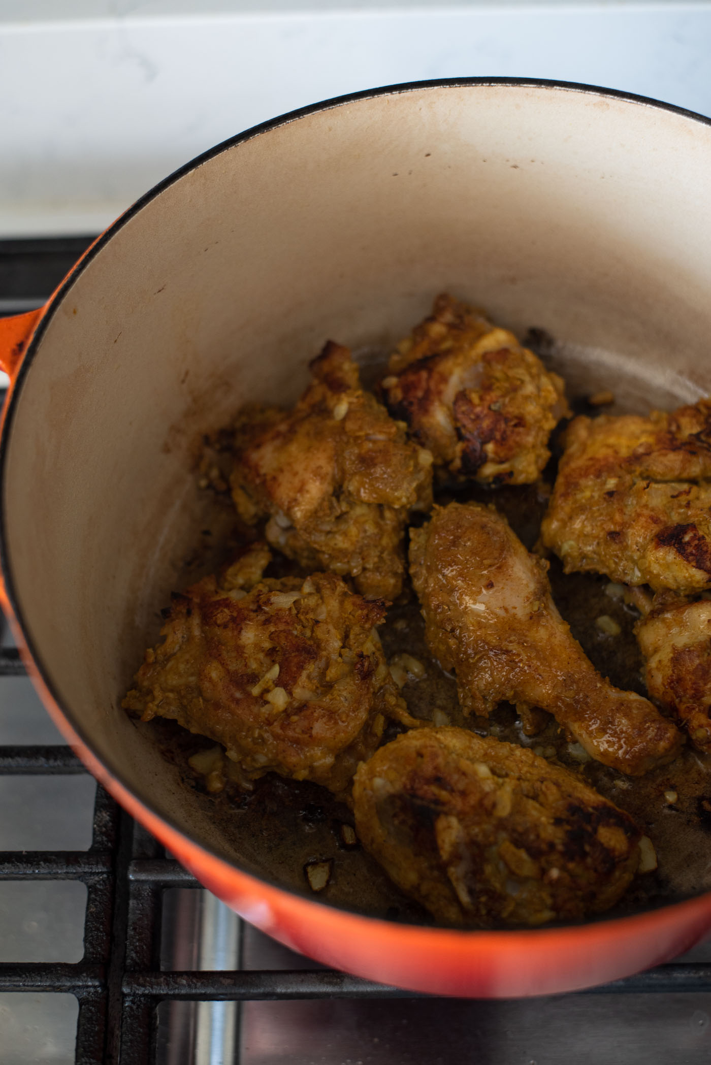 Marinated chicken parts are seared in a pot until browned on the surface