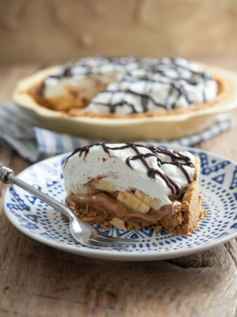 A slice of banoffee pie is served on a blue plate with a fork.