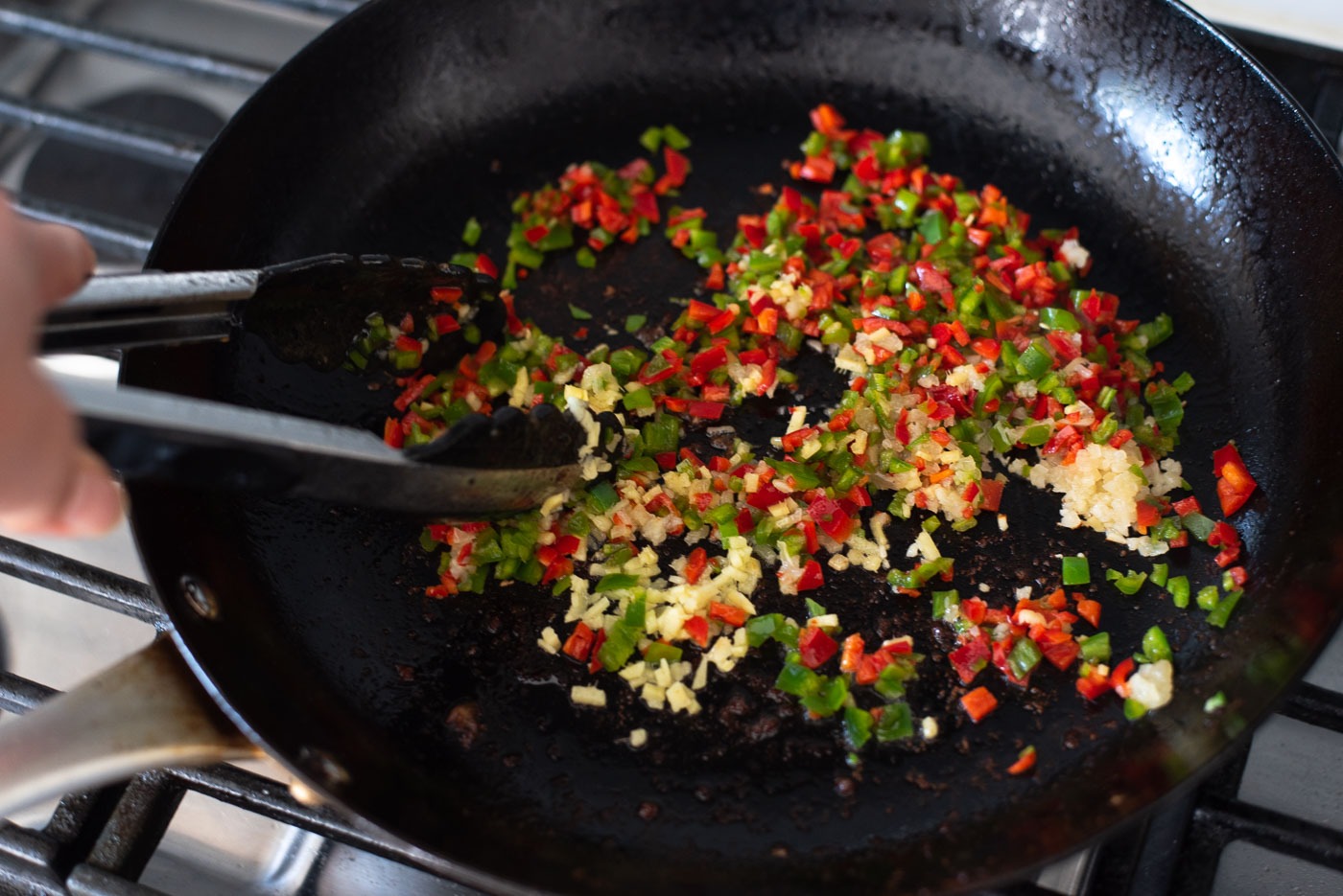 Fresh green and red chili, garlic, and ginger is stir-frying in a skillet