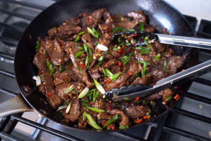 Sliced green onions are added to the cumin beef stir-fry.