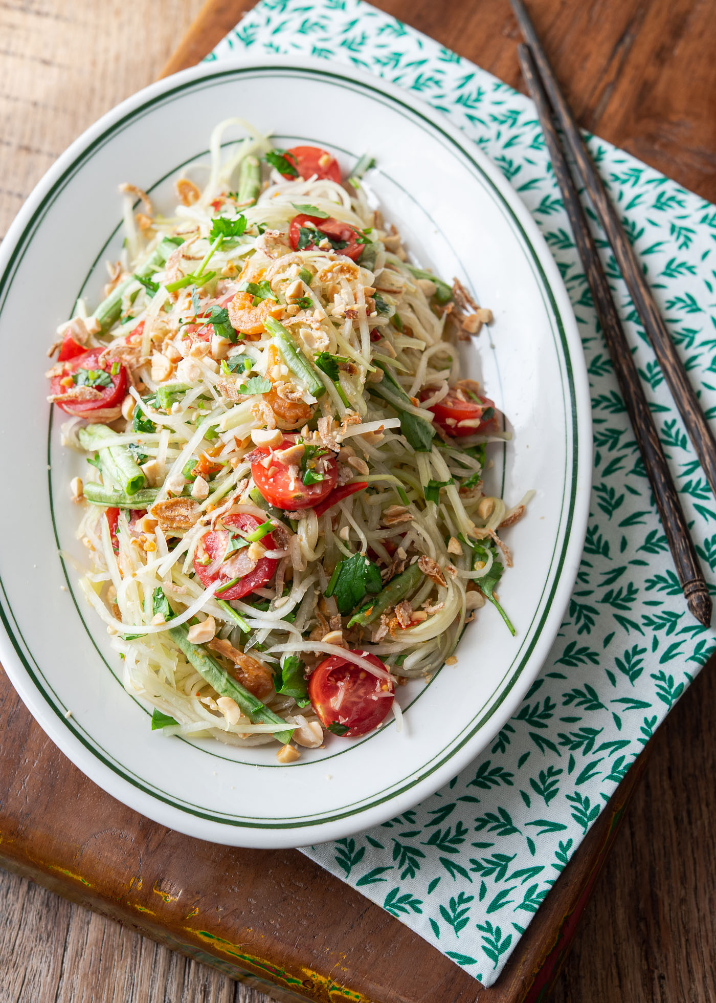 A top view of Som Tam (Thai Papaya salad) served on a white oval plate.