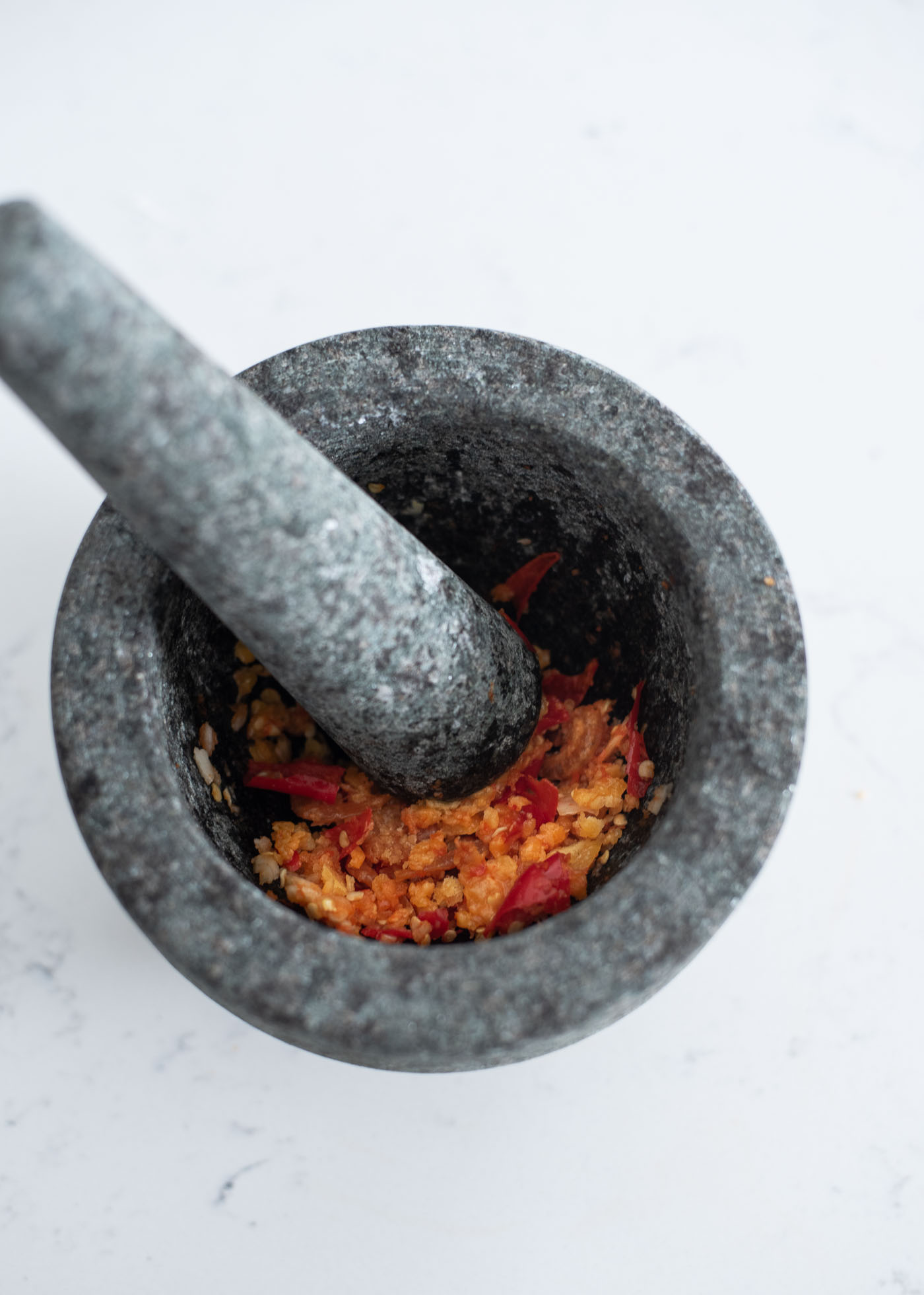 Garlic and red chili are pounded in a mortar with pestle