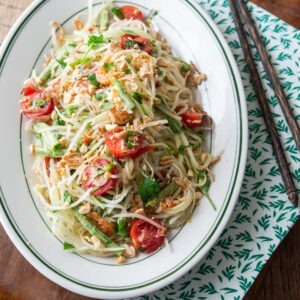 Som tam, ThaiPapaya salad, served on a white oval plate.