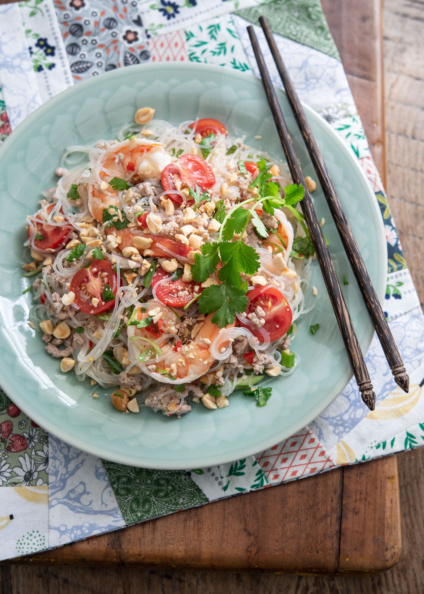 Thai glass noodle salad with shrimp is served in a green dish with chopsticks.