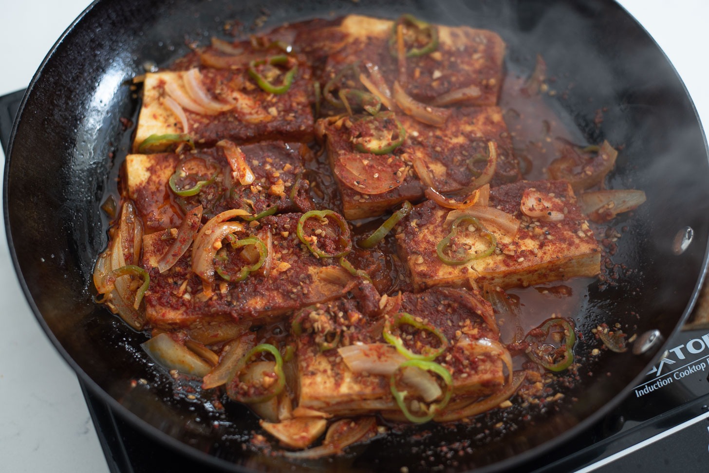 Tofu slices are are simmered in a skillet.