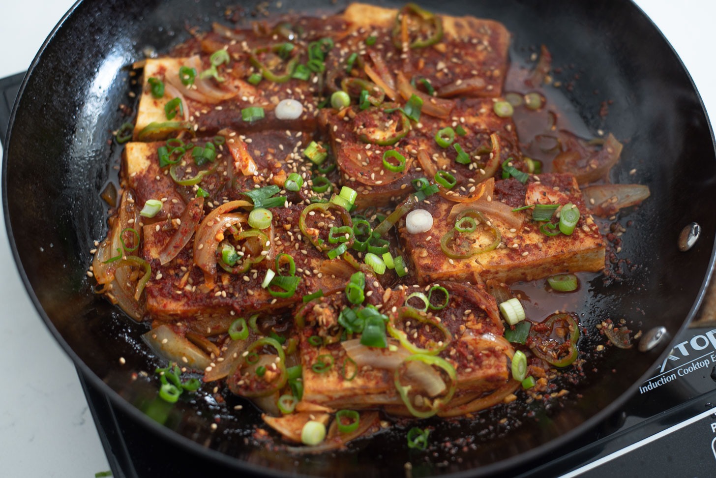 Chopped green onion are added on top of braised tofu as a garnish.
