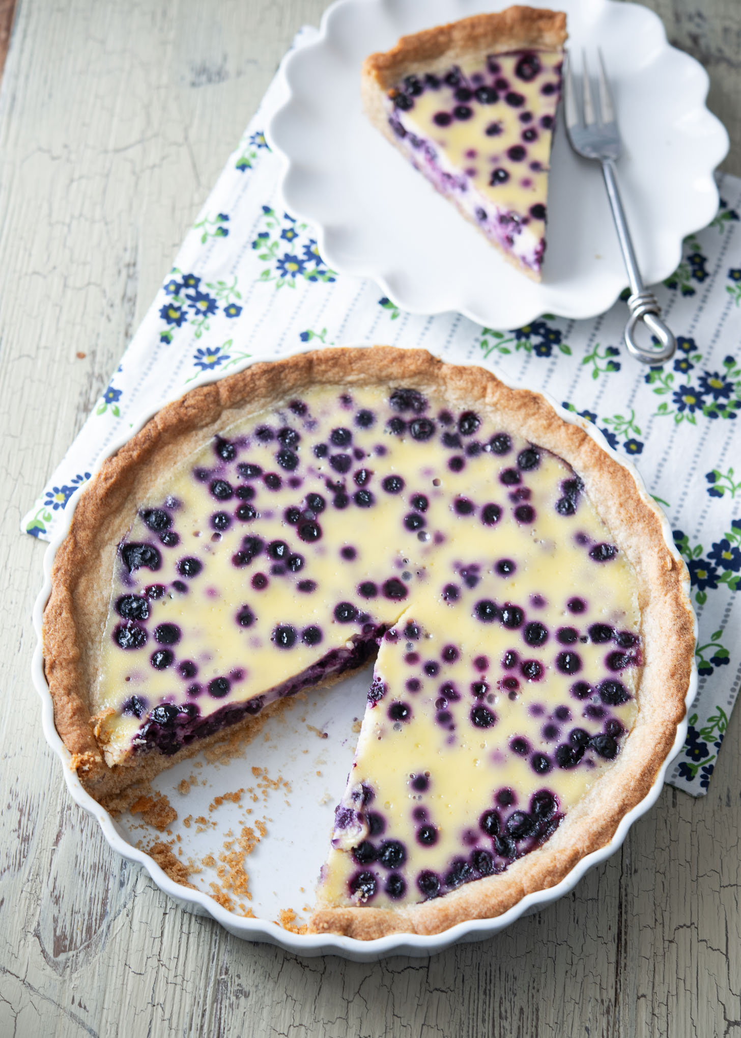 A piece of Finnish blueberry pie (Mustikkapiirakka) from a pie dish and served on a small plate.