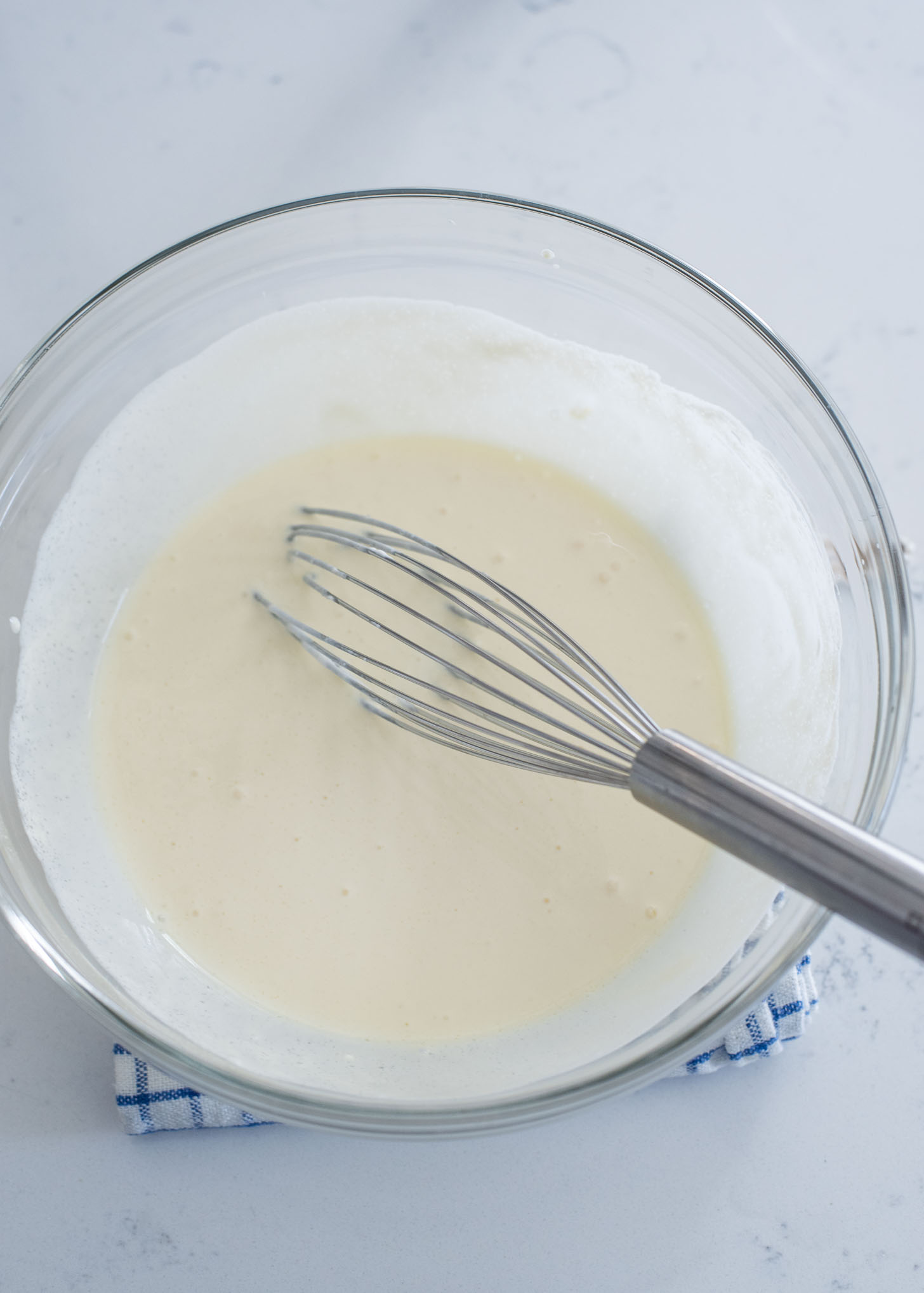 Creamy filling is mixed with a whisk in a mixing bowl.