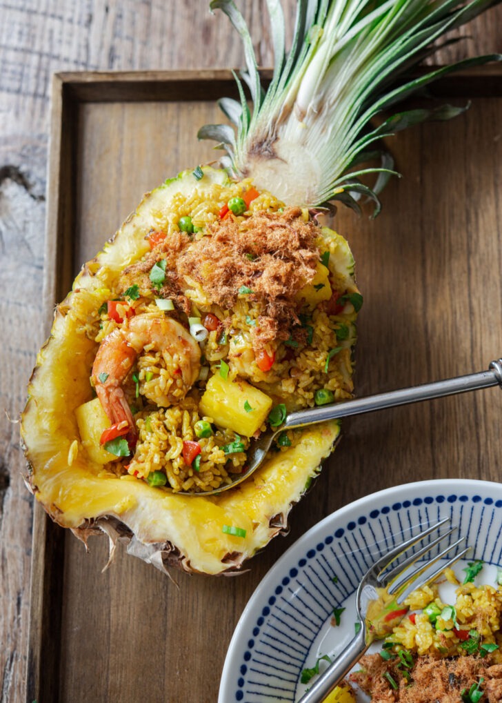 Pineapple fried rice is served in a fresh pineapple boat with a spoon