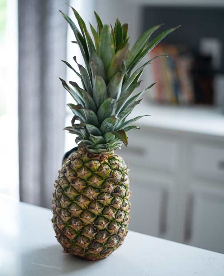 A fresh whole pineapple with leaves attached is shown.