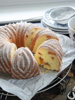 A slice of peach pound cake baked in a bundt pan is showing the cake crumb texture with peach pieces inside.
