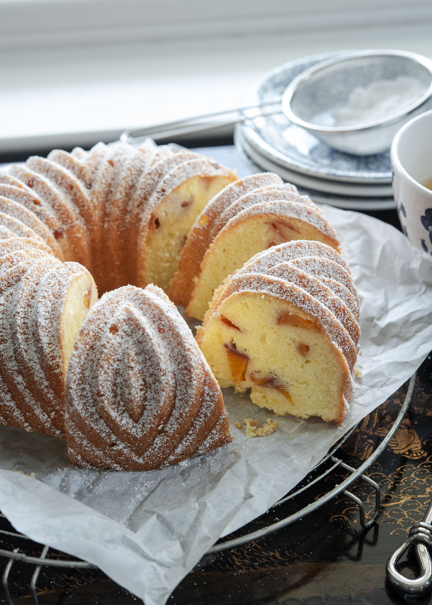 A slice of peach pound cake baked in a bundt pan is showing the cake crumb texture with peach pieces inside.