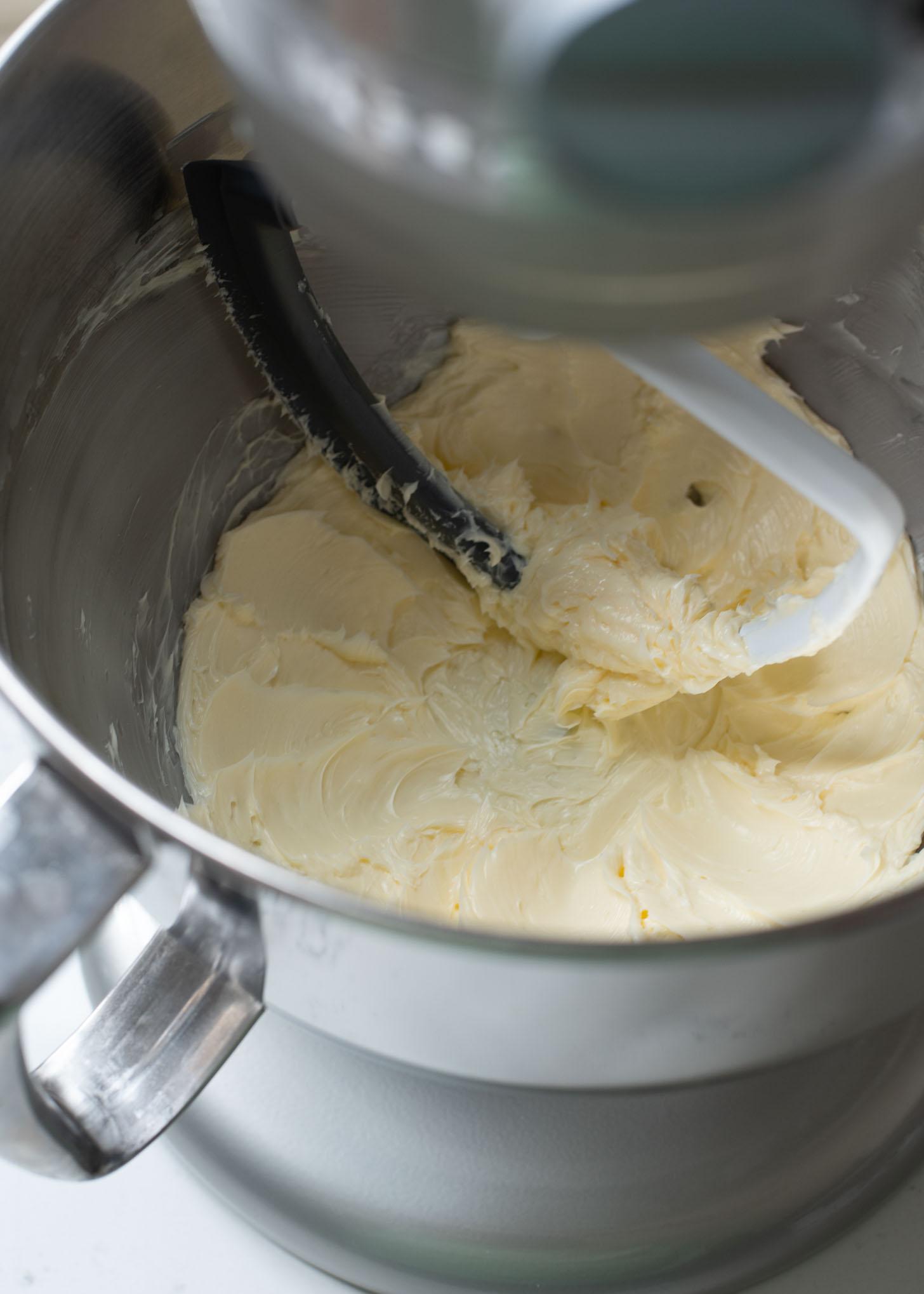 A mixer with a flat whisk is beating butter to be creamy.