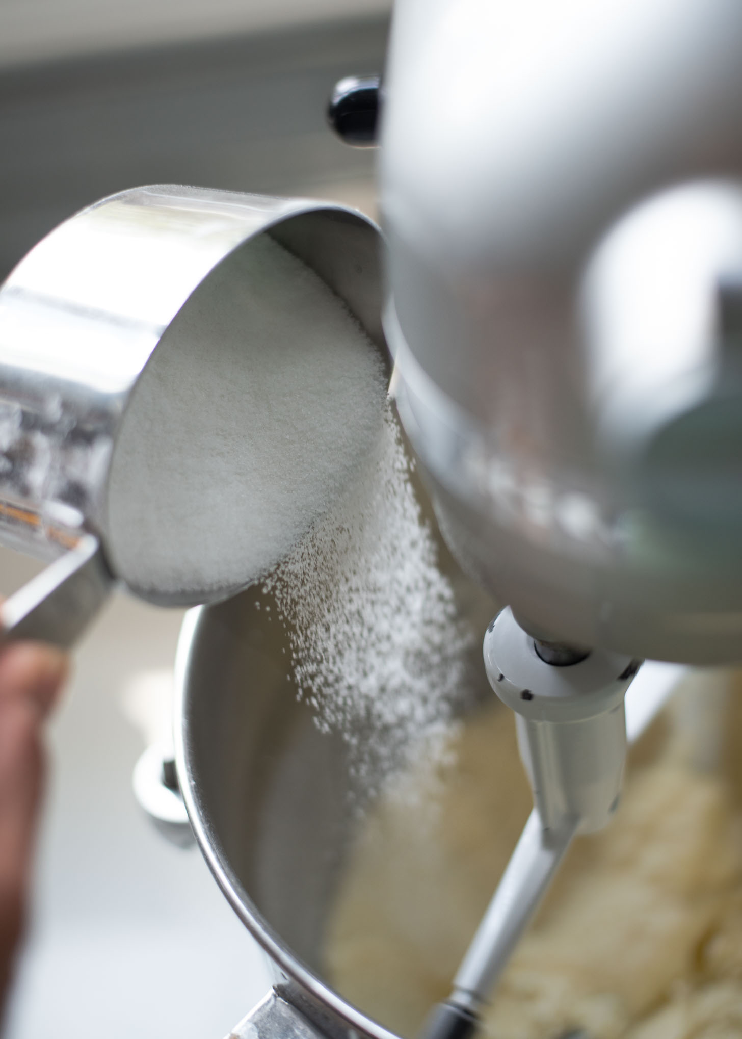 Sugar is being added gradually to creamed butter in a mixer.