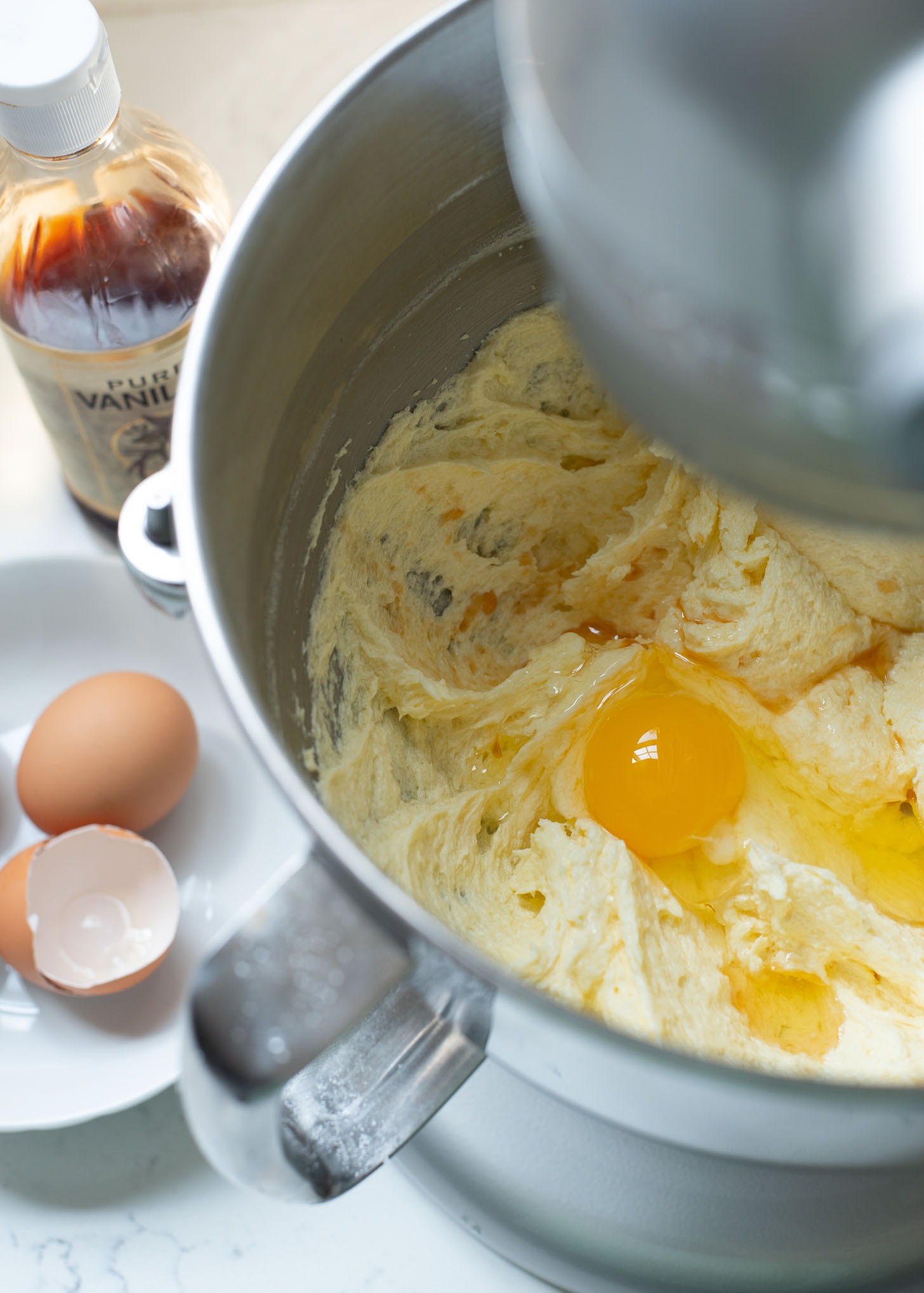 Eggs and vanilla extract are added to butter and sugar mixture in a mixer.