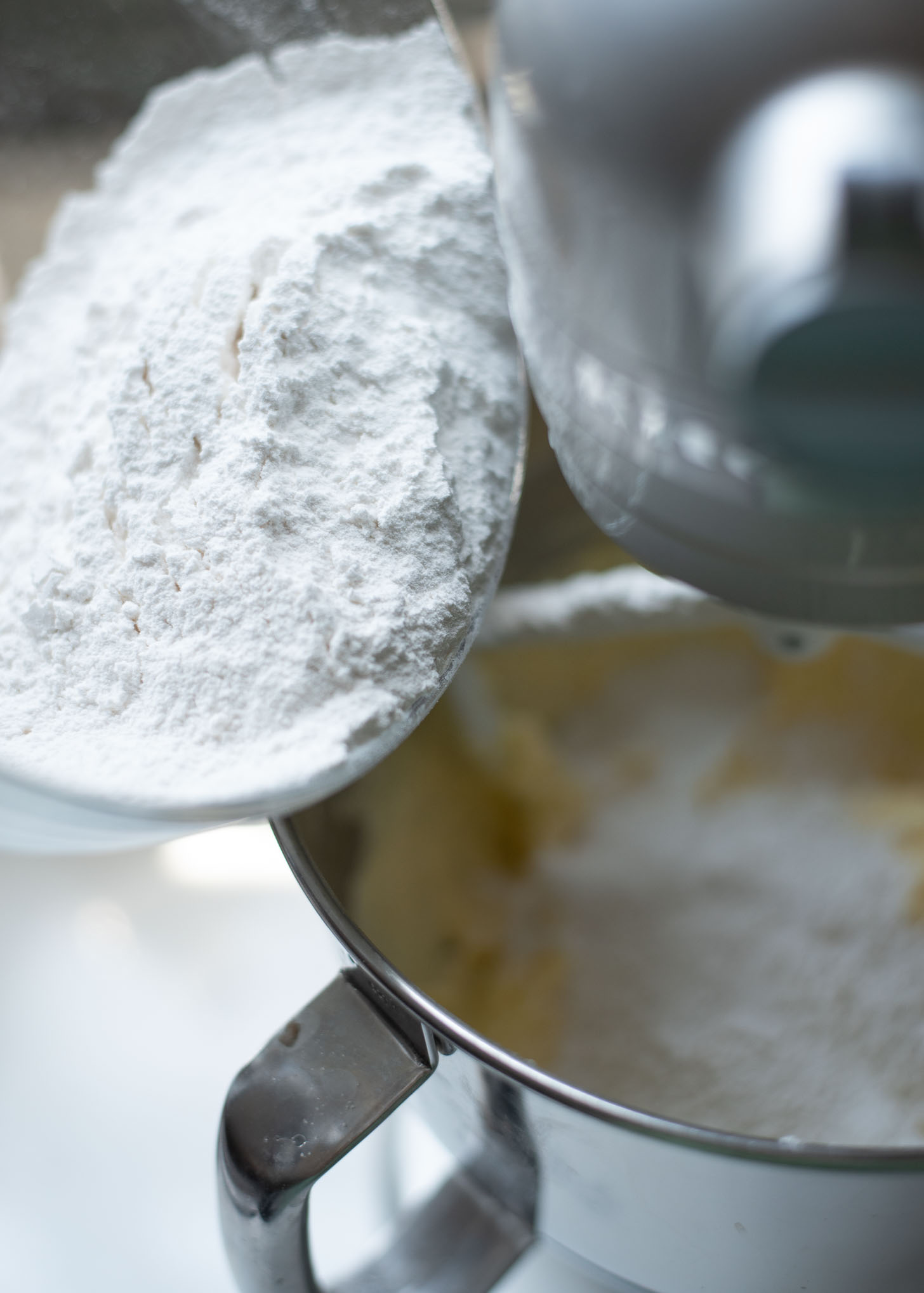 Flour mixture is being added to wet mixture in a mixer to make peach pound cake.