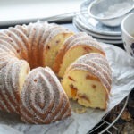 A slice of peach pound cake baked in a bundt pan is showing the cake crumb texture with peach pieces inside.