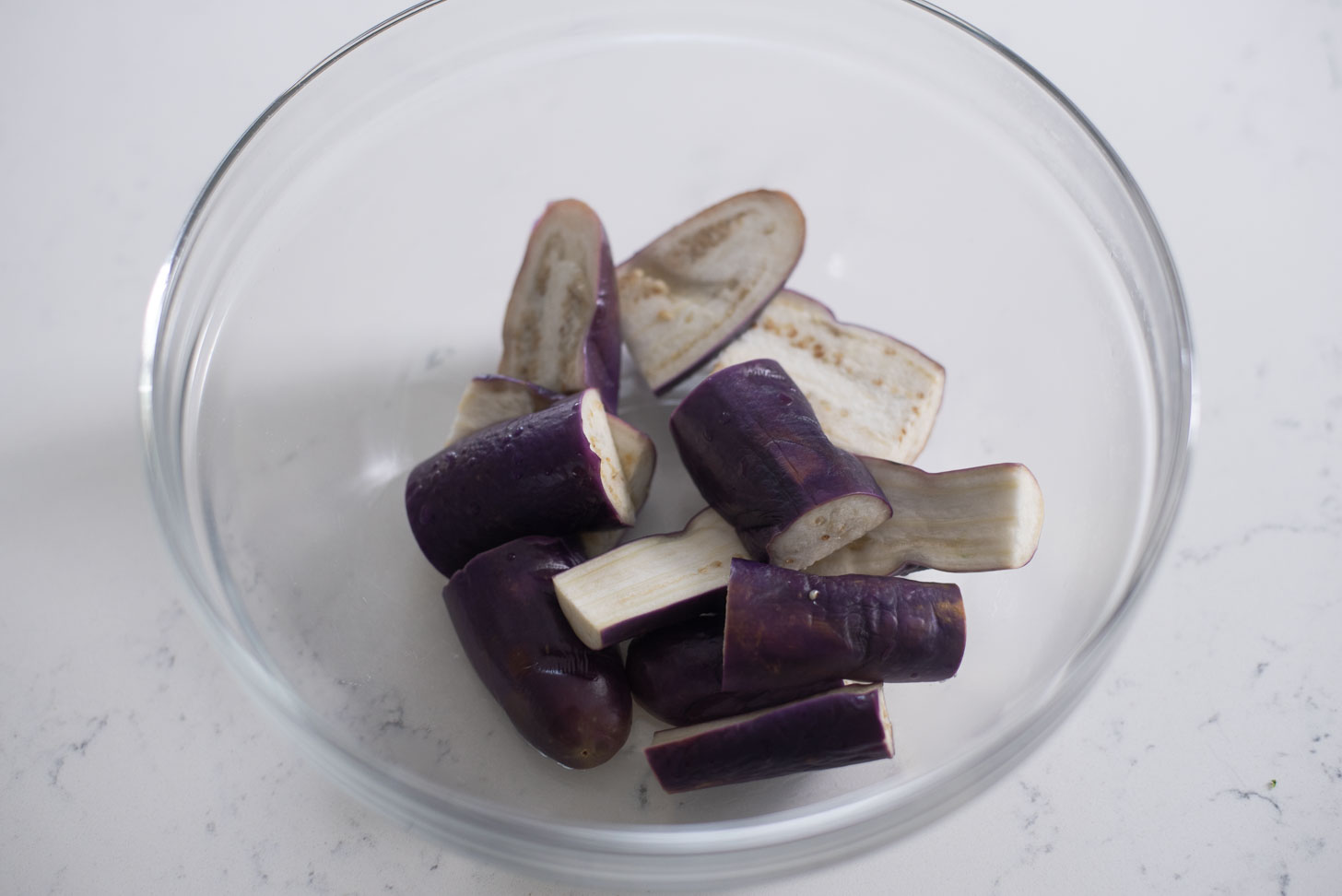 Steamed eggplants are cooling in a bowl.