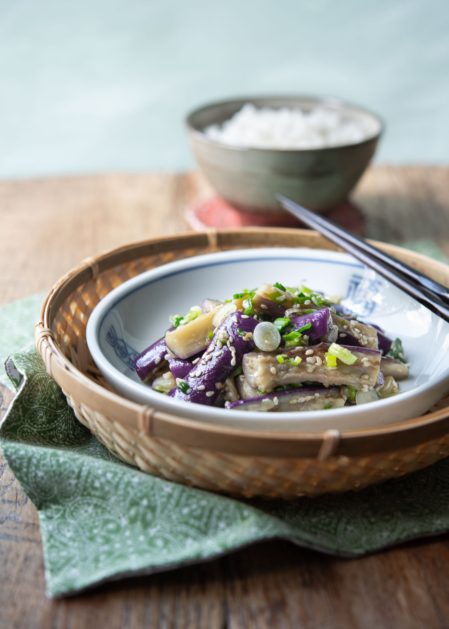 Korean eggplant side dish in a small serving dish is garnished with sesame seeds and green onion. 