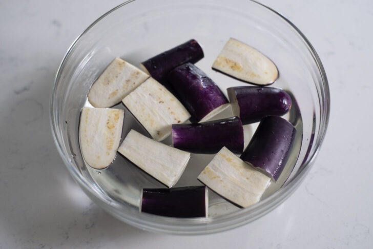 Eggplant slices are soaking in water with a little vinegar.