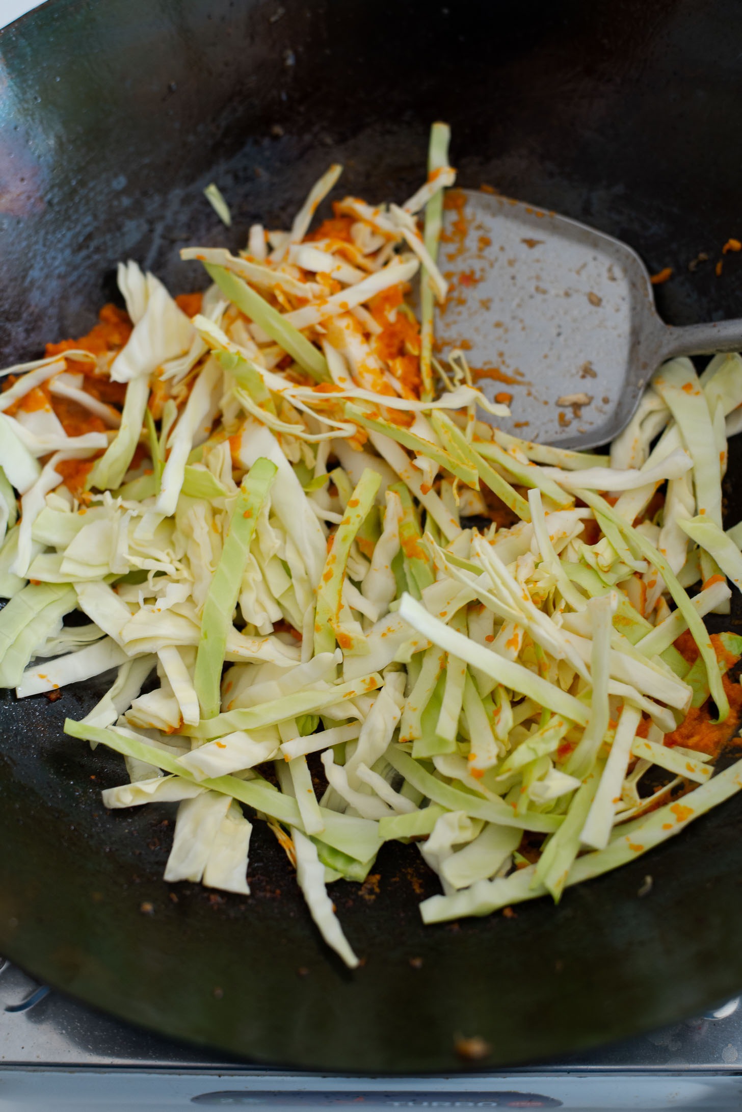 Cabbage slices are added to Nasi Goreng chili garlic in a wok 