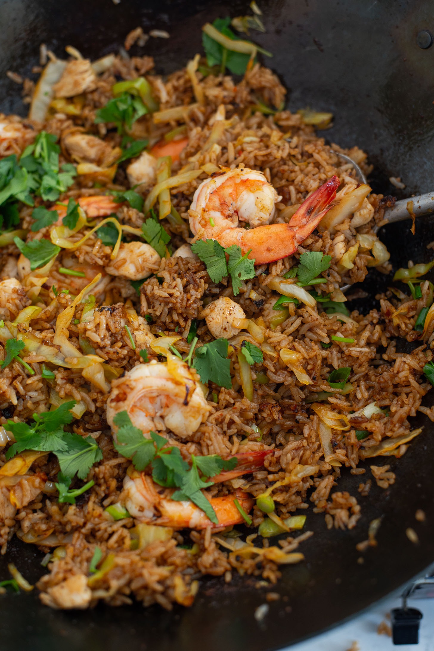 Chicken, shrimp, and Nasi Goreng sauce is added to rice in a wok.