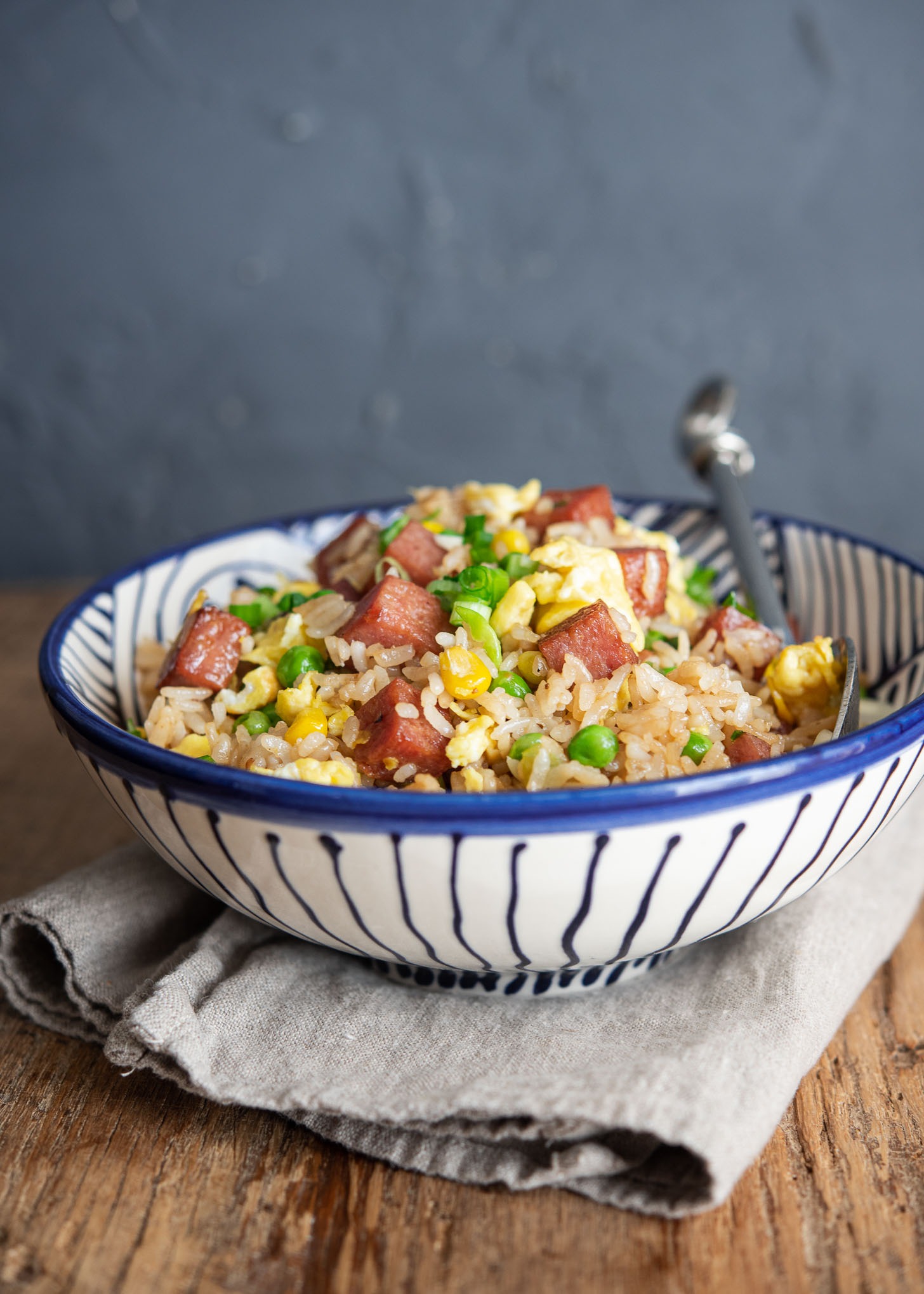 Spam fried rice is served in a bowl with a spoon